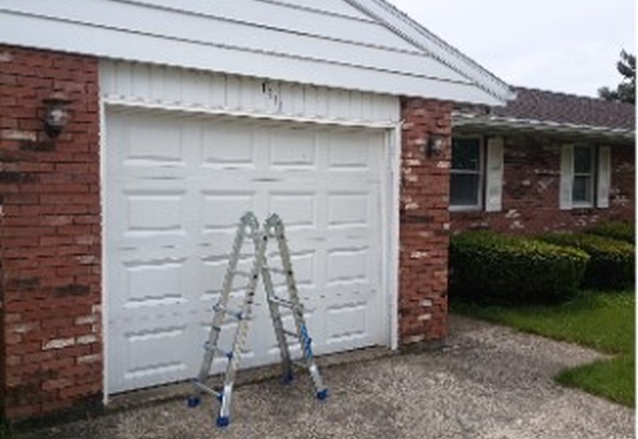Exterior home repair project with ladder by a garage